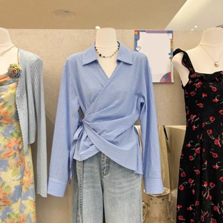 A woman in a long-sleeved shirt十三行2025春季法式翻領綁帶收腰顯瘦直條紋不規則藍色襯衫